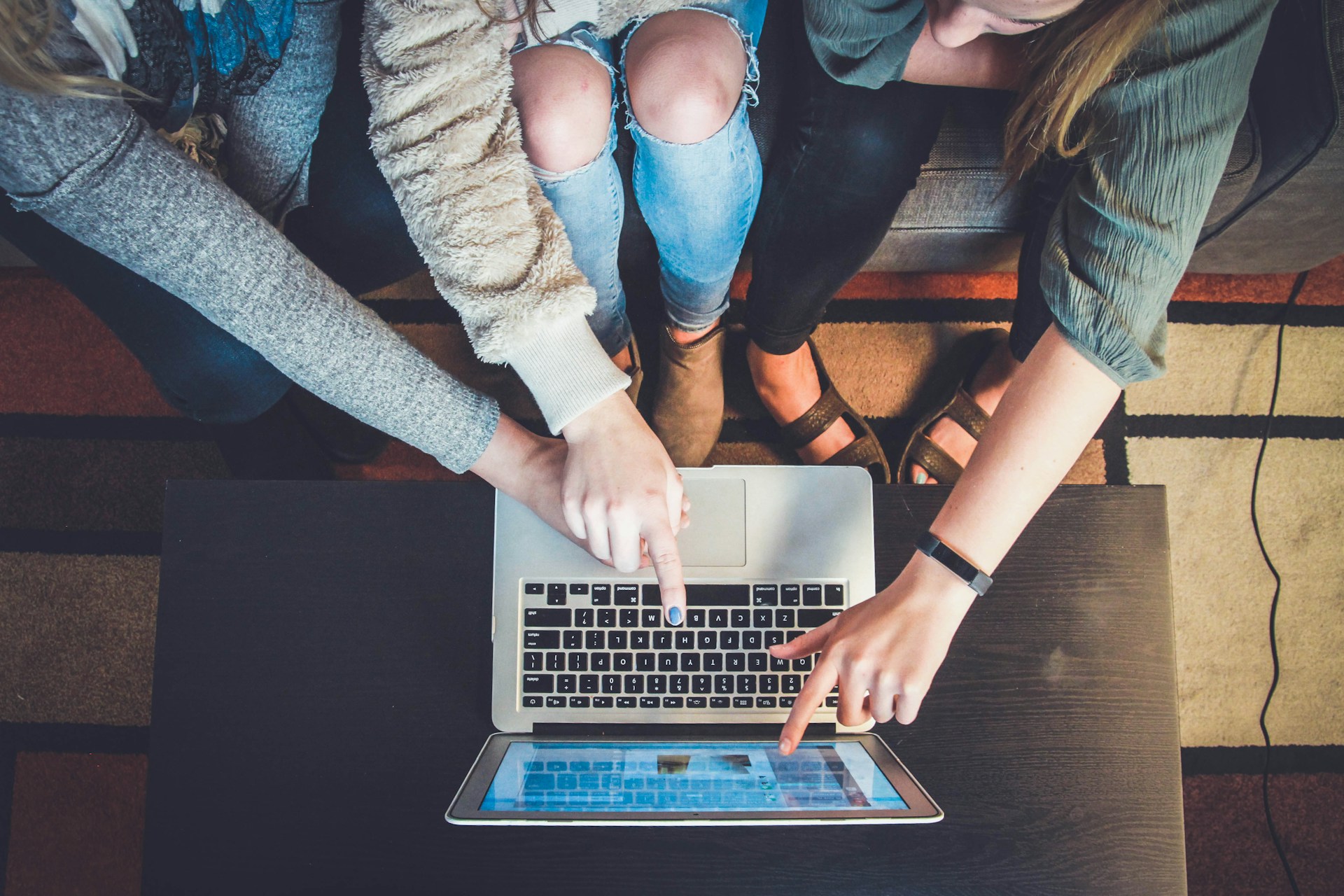 Three people pointing at a laptop
